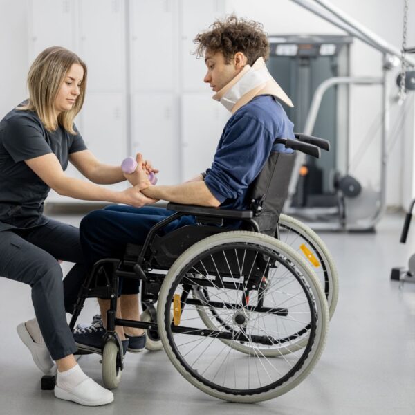 man in wheelchair and neck brace working with a pt