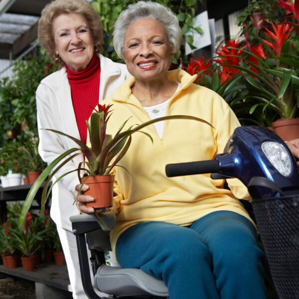 person sitting on a medical scooter holding a plant