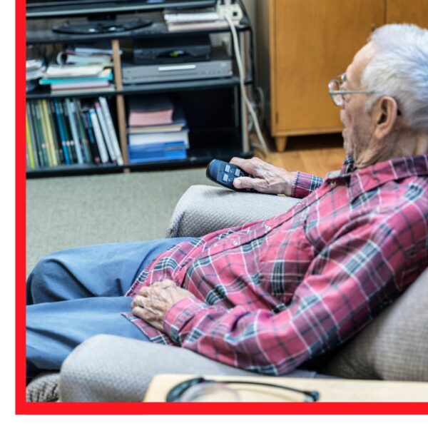 Older man sitting in chair, holding remote