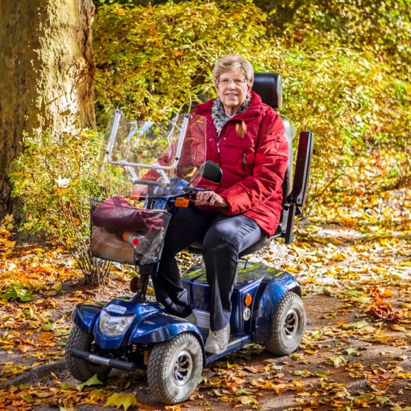Old lady writing her scooter through the woods