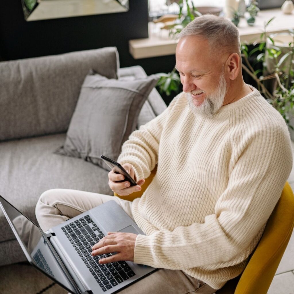 A man using his phone and a laptop